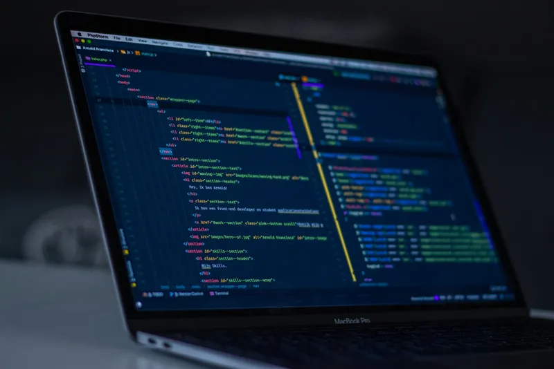 Office desk with two monitors showing programming code in an editor