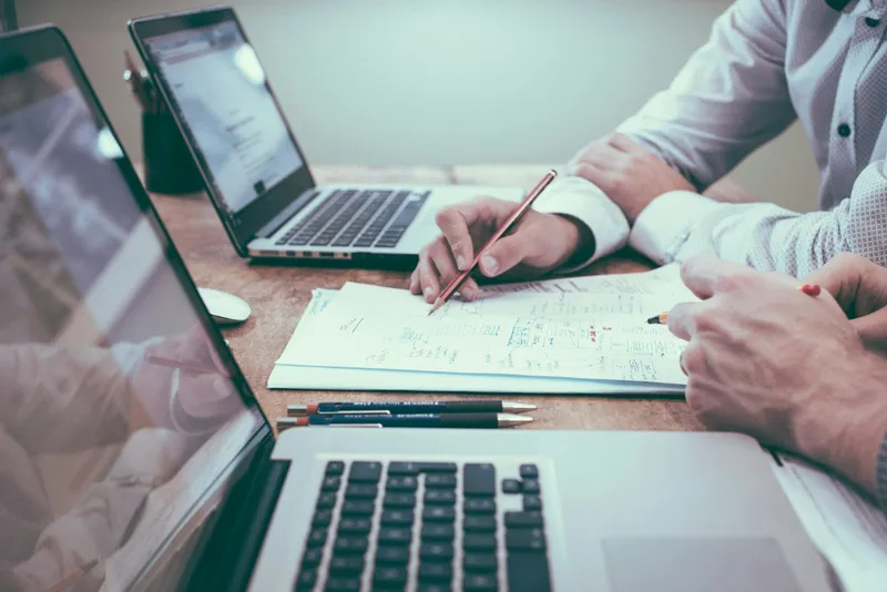 Hands holding a pen over paperwork on a desk