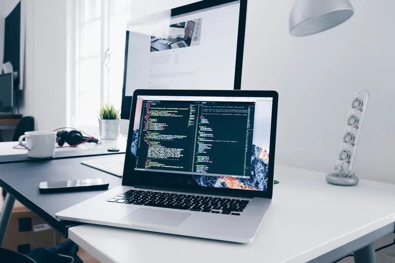 Laptop on a desk showing code on screen